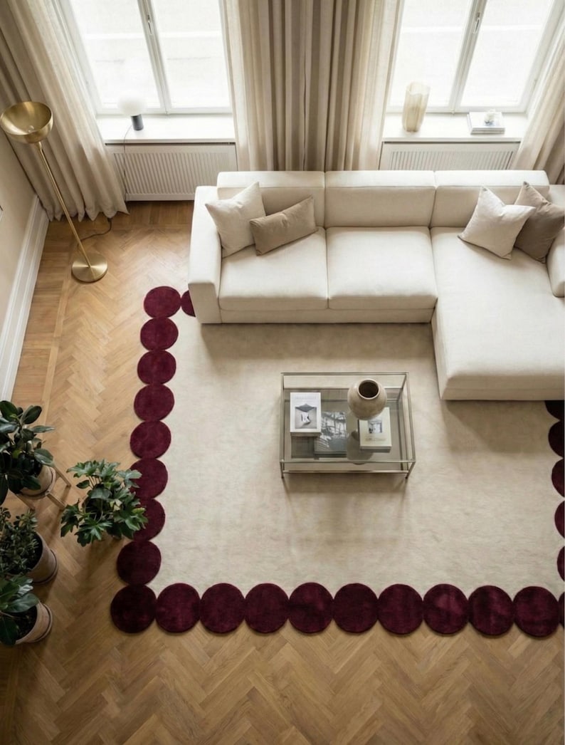 Contemporary burgundy scallop edge rug 5x8 crafted by artisans using hand tufting techniques. The elegant round shapes wrap around the neutral middle, creating depth and movement. Perfect for apartments, bedrooms or chic sitting areas where a bold but refined carpet is desired.