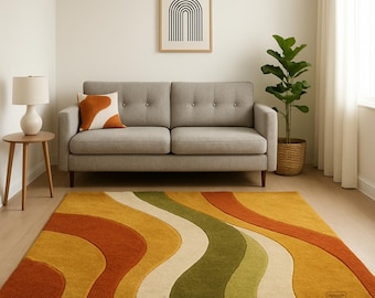 May include: A living room with a grey sofa, side table with a lamp, and a large rug. The rug features a wavy pattern in yellow, orange, green, and cream. A framed artwork hangs on the wall above the sofa.