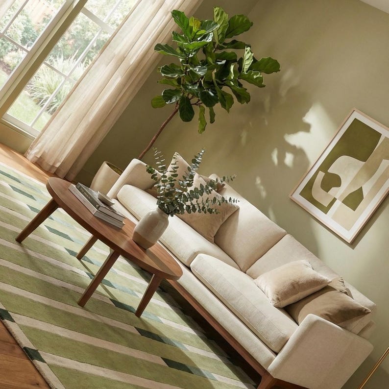 Elegant hand tufted area rug in soothing green tones with striped design, styled in a minimalist living room with wooden flooring. Crafted from high-quality wool, this rug provides comfort, durability, and timeless style. Perfect for modern home decor, this handmade wool rug works well in living rooms and bedrooms. Available in standard sizes including 5x8, 6x9, and 8x10 feet, with custom sizing available.