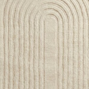 Large 8x10 hand tufted area rug in soft cream color with elegant abstract swirl lines. Placed under a modern wooden coffee table and neutral couch, this wool carpet enhances warm wooden flooring and airy spaces. Designed for minimalist and modern homes, the rug provides comfort, durability, and timeless style. Great choice for living room, bedroom, nursery, or reading corner needing a calm and sophisticated foundation.