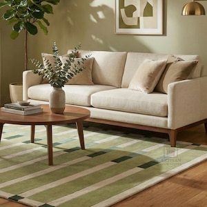 Hand tufted green striped area rug placed in a modern living room with beige sofa and wooden floor, featuring soft wool texture and clean striped design. This handmade rug adds warmth and elegance to home decor, ideal for living room, bedroom, or office space. Available in sizes 5x8 ft, 6x9 ft, and 8x10 ft, this contemporary green wool rug complements minimalist, boho, and modern interiors beautifully.