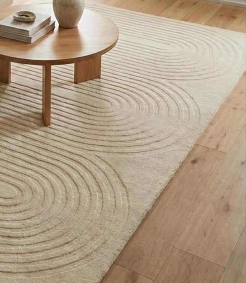 Beige wool hand tufted carpet 8x10 designed with flowing curved lines and plush texture. A perfect anchor for modern interiors, this large rug pairs effortlessly with neutral furniture and natural materials. Ideal for living rooms, bedrooms, studios, or calm relaxing environments. Adds warmth, sophistication, and a designer touch to everyday spaces.