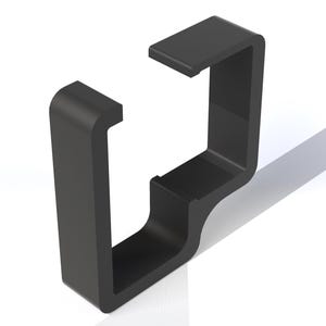 Puede incluir: Un soporte negro en forma de U con una parte superior rectangular y una base curva. El soporte está hecho de un material sólido y proyecta una sombra sobre la superficie blanca de abajo. El diseño es moderno y minimalista.