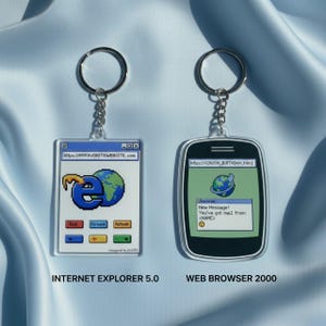 Könnte beinhalten: Zwei Schlüsselanhänger mit silbernen Ringen. Einer zeigt ein pixeliges Internet Explorer 5.0-Design mit dem Text "https://MYFAVORITEWEBSITE.com". Der andere zeigt ein Web Browser 2000-Design mit einer Nachrichtenbenachrichtigung.
