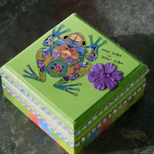 May include: Green wooden box featuring a colourful frog design and the text "Your tribe is your vibe". The box has a beaded trim around the edges.