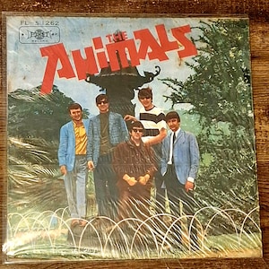 May include: Vintage vinyl record album cover for The Animals, featuring a group photo of the band. The album title is in large red letters. The cover has a retro aesthetic, with a photo of the band members in suits and sunglasses.