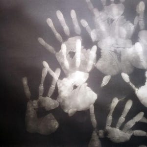 Pode incluir: Imagem monocromática com múltiplas impressões de mãos brancas sobre um fundo escuro. As impressões variam em tamanho e sobrepõem-se, criando um padrão texturizado. A imagem tem uma qualidade artística de alto contraste.