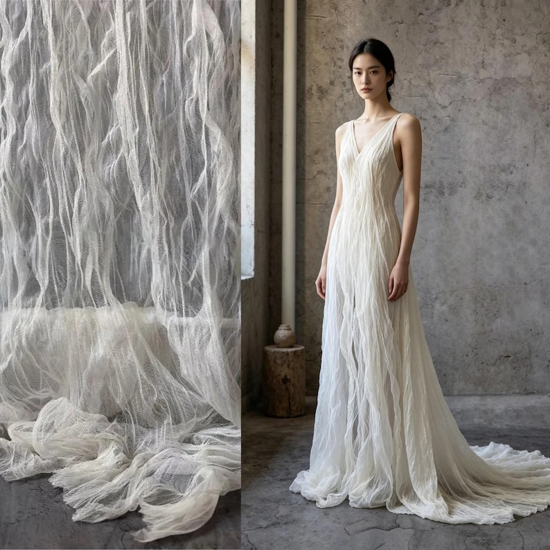 Puede incluir: Un vestido blanco sin mangas hasta el suelo con escote en V y una capa de tela texturizada y arrugada que crea pliegues verticales que caen hasta el suelo, formando una cola que se extiende por el suelo en una silueta fluida.