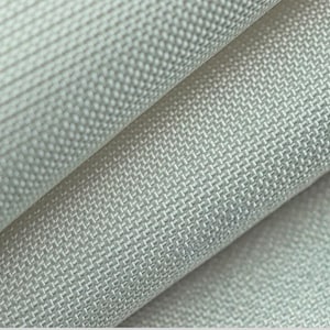 May include: Close-up of a light gray woven fabric with a textured surface. The fabric is folded, revealing layers and subtle variations in the weave pattern. The material appears to be durable and suitable for upholstery or home decor.