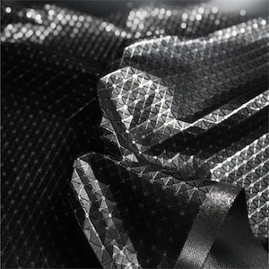 May include: A black fabric featuring a reflective, geometric grid pattern composed of small, raised triangular shapes. The material has a high-contrast, textured surface with bright white light points highlighting the edges of the grid structure.