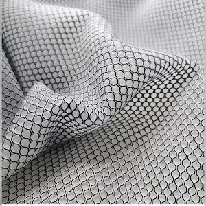 May include: Close-up of a white fabric with a black honeycomb pattern. The fabric is draped, showing the texture and design. The pattern is consistent throughout the material, creating a visually interesting surface.
