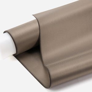 May include: A roll of taupe-colored fabric, partially unrolled to reveal its texture. The fabric is a solid color and appears to be tightly woven. The roll is on a white cardboard tube.