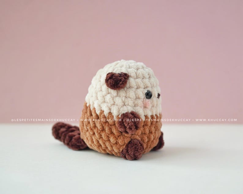 K&ouml;nnte beinhalten: Ein handgefertigtes geh&auml;keltes Otter-Pl&uuml;schtier in Creme, Braun und Dunkelbraun. Der Otter hat einen cremefarbenen Kopf mit dunkelbraunen Ohrakzenten, einen braunen K&ouml;rper und einen dunkelbraunen Schwanz.