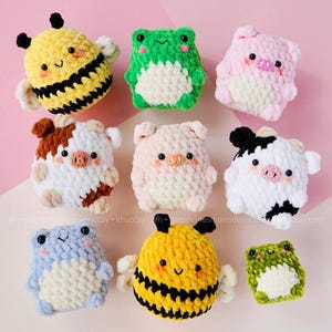 May include: A collection of handmade crochet plushies in various animal shapes, including bees, frogs, pigs, and cows. The plushies are in vibrant colors like yellow, green, pink, and white, with detailed facial features and small wings. The background is a soft pink.