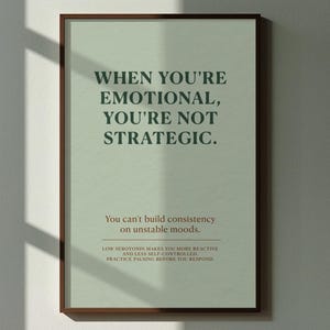 May include: A framed print with the text "WHEN YOU'RE EMOTIONAL, YOU'RE NOT STRATEGIC." hangs above a wooden bench. The print has a light green background and a dark brown frame. The text "You can't build consistency on unstable moods" is also visible.
