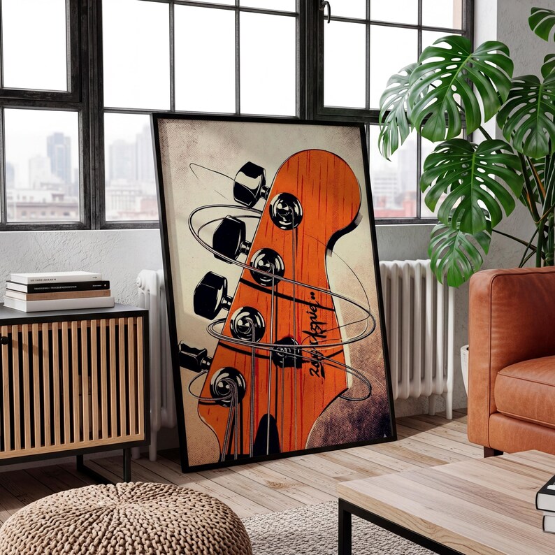 May include: A framed art print featuring a close-up of a bass guitar headstock. The headstock is orange with black tuning pegs and strings. The artwork has a vintage, distressed look with a cream-colored background and a black frame.