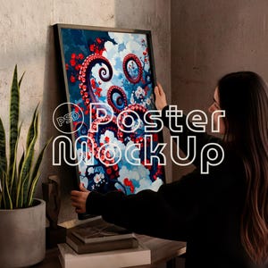 May include: A framed art print with an octopus design, featuring red tentacles, white flowers, and blue and white clouds. The artwork is displayed on a wooden surface. The text "Poster Mockup" is overlaid on the image.