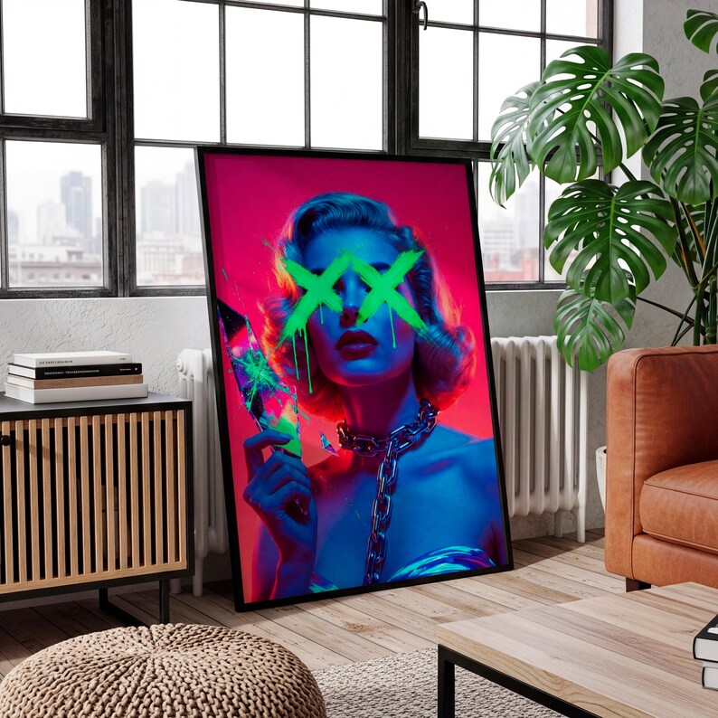 May include: A framed art print featuring a woman with green neon 'XX' marks over her eyes, holding a broken object. The artwork uses a vibrant color palette of pink, blue, and green, with a silver chain necklace. The print is displayed in a modern living room setting.