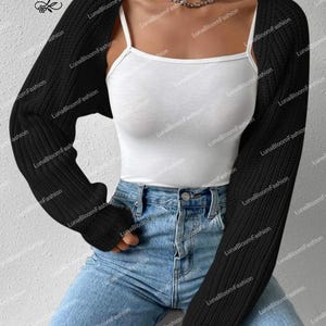May include: A black, long-sleeved bolero cardigan. The cropped cardigan is worn over a white vest top and paired with blue jeans. A silver chain necklace is visible. The brand name "LunaBloomFashion" is printed on the image.