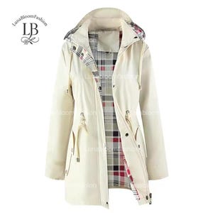 Puede incluir: Chaqueta con capucha color crema con cintura ajustable con cordón y forro a cuadros. La chaqueta tiene cierre de cremallera y botones de presión. La marca "LunaBloomFashion" es visible.