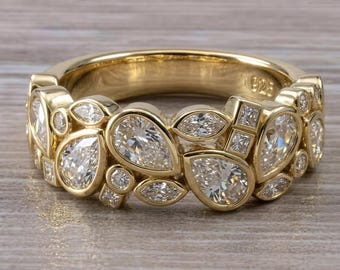 May include: A gold-toned ring featuring a cluster of clear, faceted stones in pear, marquise, and square shapes. The band is crafted with a polished finish and includes a 925 hallmark stamp on the interior, indicating sterling silver construction.
