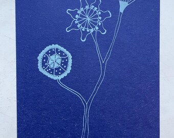 May include: A blue card features a light blue botanical illustration. The artwork depicts a central stem with two flower-like shapes and a third, more complex, fan-shaped design. The artist's signature is in the lower right corner.
