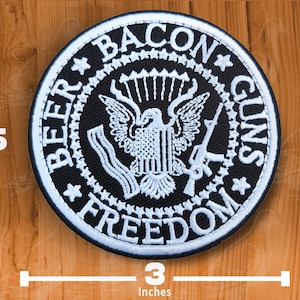 Può includere: Una toppa rotonda ricamata in bianco e nero, di 7,6 cm di diametro, con la scritta "BEER BACON GUNS FREEDOM" attorno a un'aquila. La toppa è alta 6,35 cm.