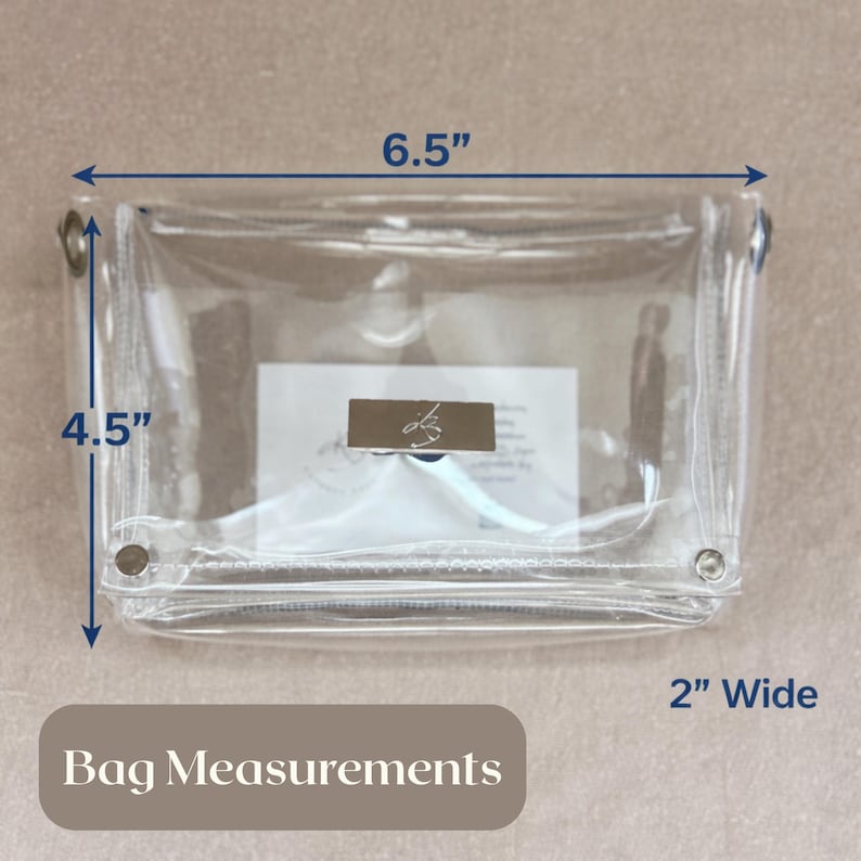 May include: A clear rectangular pouch with a silver-toned metal clasp featuring a logo. The bag measures 6.5 inches in length, 4.5 inches in height, and 2 inches in width. The design includes metal grommets on the sides and a zipper closure.