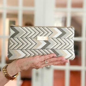 Cartera de cincha estampada en gris, blanco y tostado con ranuras para tarjetas integradas, bolsillo abierto y cierre de cremallera.