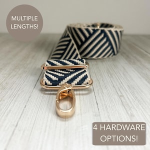 Puede incluir: Una correa de bolso tejida en azul marino y crema con un patrón de chevrón diagonal, equipada con herrajes de metal en tono dorado, incluyendo un ajustador deslizante y un mosquetón giratorio. La imagen incluye el texto MULTIPLE LENGTHS! y 4 HARDWARE OPTIONS!