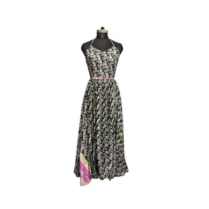 Puede incluir: Un vestido largo negro con cuello halter y un estampado de elefantes en crema y dorado. El vestido tiene un ribete rosa alrededor del escote y la cintura, y un panel estampado en rosa y morado en la falda.