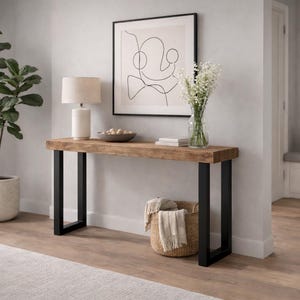 May include: A wooden console table with black metal legs, a white lamp, and a framed abstract art piece. A potted plant and a woven basket add to the room's decor. The table is approximately 152 cm long.