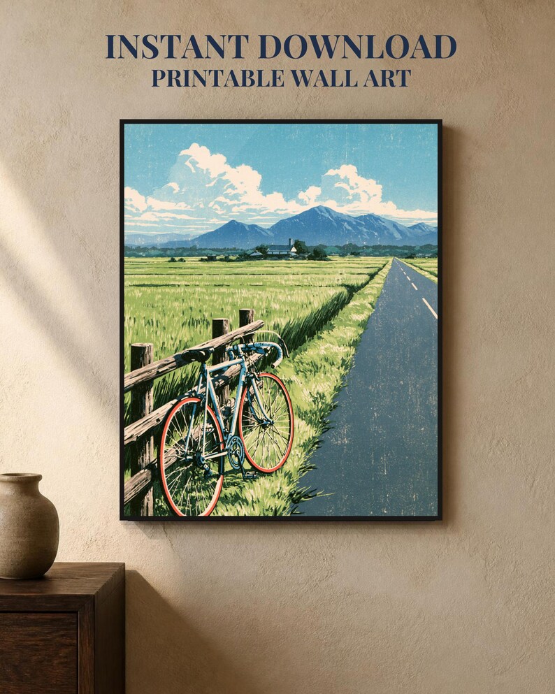 May include: A framed wall art print featuring a blue bicycle leaning against a wooden fence beside a road. The scene depicts a green field, distant mountains, and a blue sky with white clouds. Text at the top reads INSTANT DOWNLOAD PRINTABLE WALL ART.