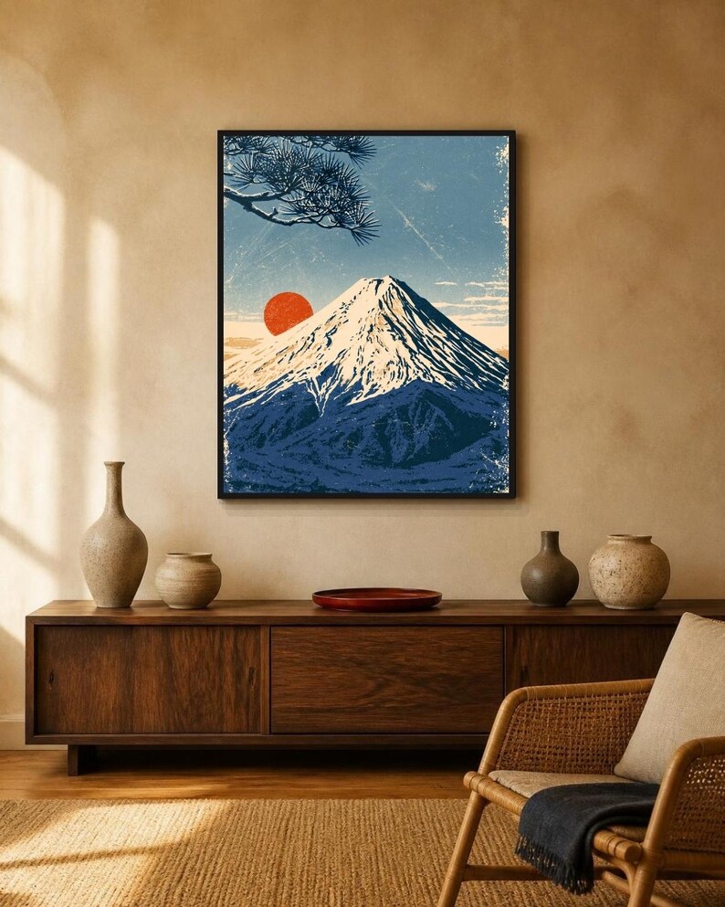 May include: A framed wall art print featuring a stylised illustration of a snow-capped mountain peak under a blue sky with a prominent red sun and dark pine tree branches in the upper left corner, rendered in a textured, vintage-inspired aesthetic.