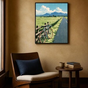 May include: A framed wall art print depicting a landscape scene with a bicycle leaning against a wooden fence beside a paved road, overlooking a green field with distant mountains under a blue sky with white clouds.