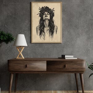 May include: A framed wall art print featuring a black ink illustration of a person with long hair and a crown of roses on their head. The person has their head tilted back with eyes closed, and the ink appears to drip down from the hair.