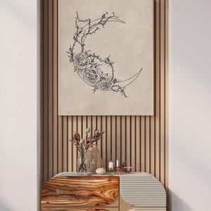 May include: A rectangular wall art print featuring a black line drawing of a crescent moon adorned with detailed roses and thorny vines on a beige background. The artwork is displayed in a thin frame, showcasing a botanical and celestial design.