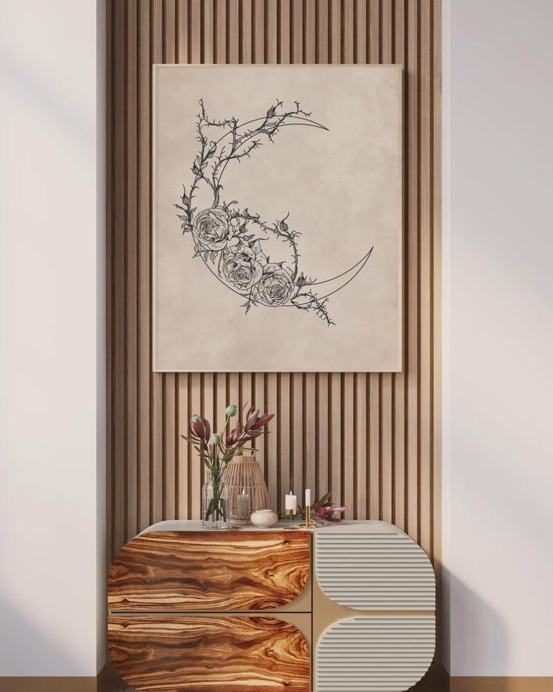 May include: A rectangular wall art print featuring a black line drawing of a crescent moon adorned with detailed roses and thorny vines on a beige background. The artwork is displayed in a thin frame, showcasing a botanical and celestial design.