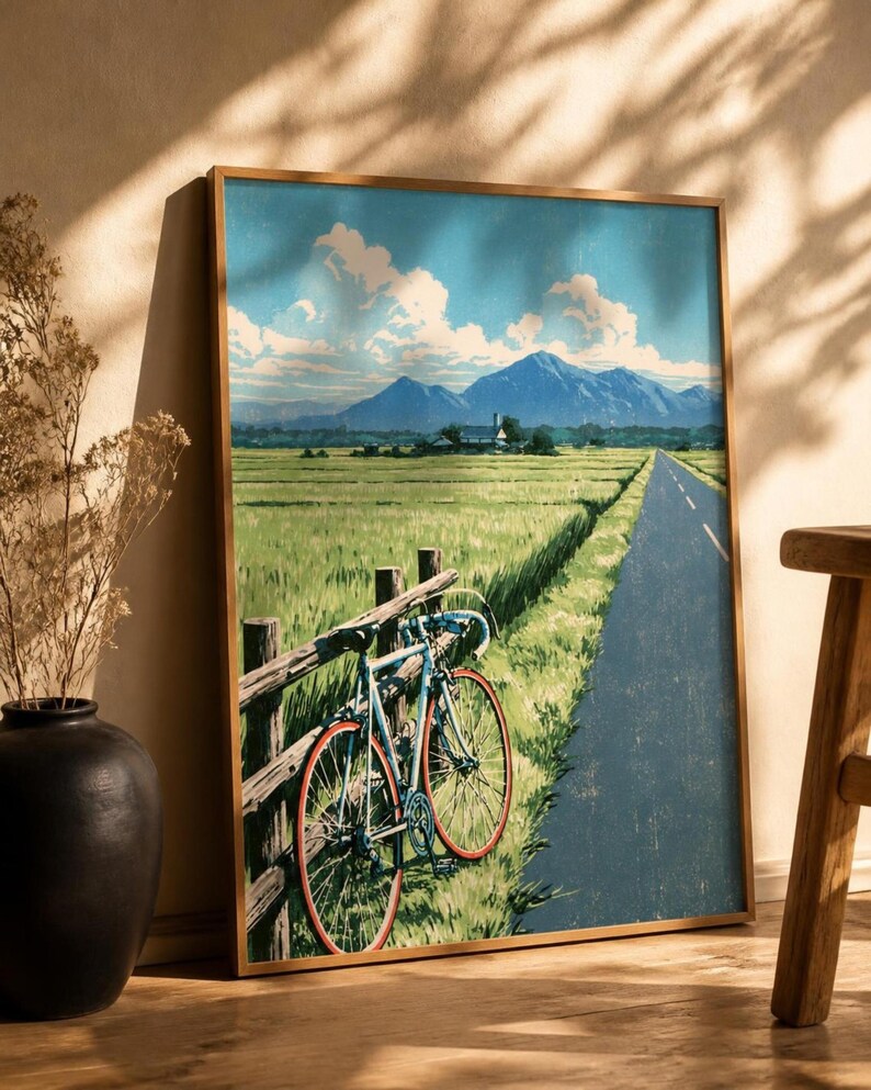 Japanese wall art poster of a bicycle and rice fields leaning against white bookshelves in a bright home interior