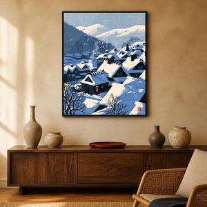 May include: A framed wall art print depicting a snowy Japanese village scene with dark wooden houses, thick white snow on roofs, a single glowing red lantern, and distant mountains under a blue sky, rendered in a stylized graphic illustration.