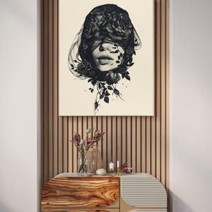 Op de afbeelding: Een vierkante wandkunstprint met een zwart-witillustratie van een gezicht dat gedeeltelijk wordt bedekt door een donkere sluier en bloeiende rozen. Het kunstwerk staat op een cr&egrave;mekleurige achtergrond in een dunne houten lijst.