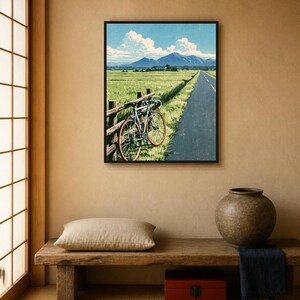 May include: A framed wall art print depicting a blue bicycle leaning against a wooden fence beside a paved road. The scene features a green field, distant mountains under a blue sky with white clouds, and a textured, vintage-style finish.