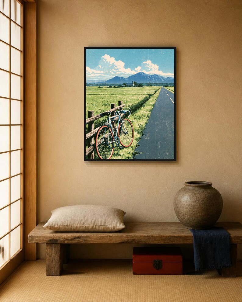 May include: A framed wall art print depicting a blue bicycle leaning against a wooden fence beside a paved road. The scene features a green field, distant mountains under a blue sky with white clouds, and a textured, vintage-style finish.