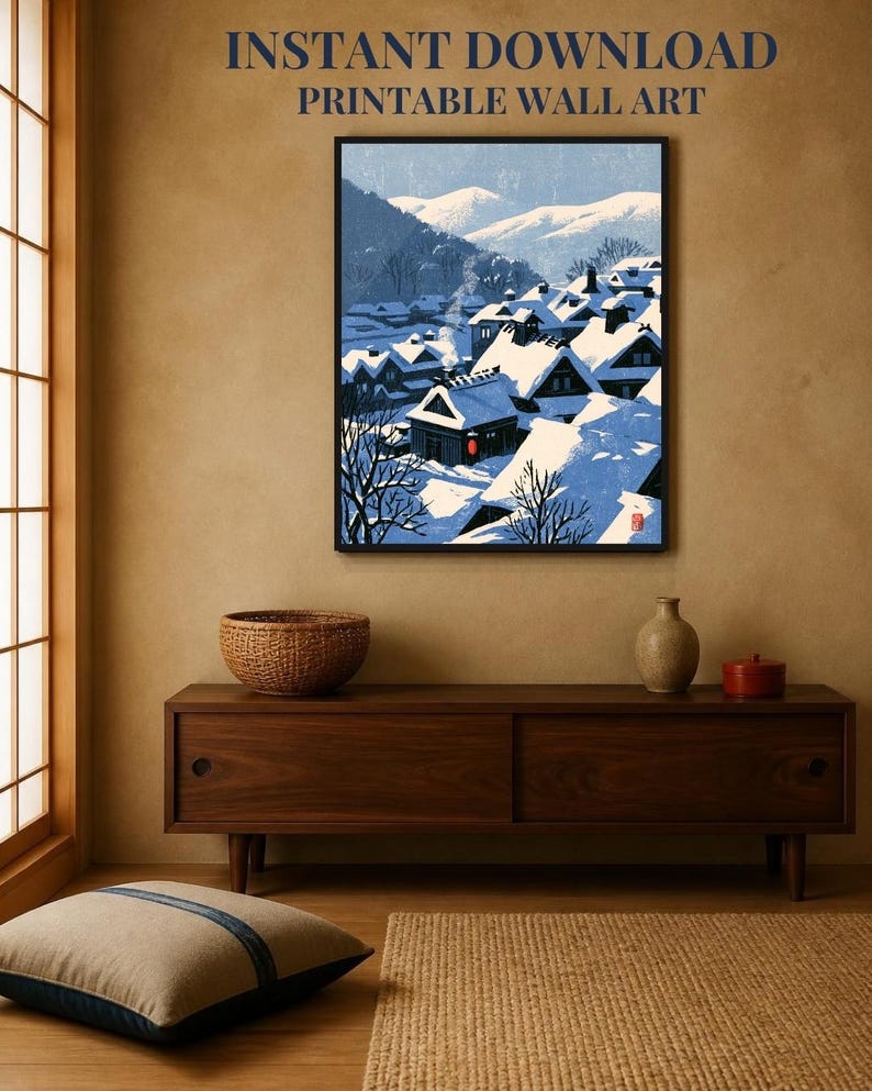 May include: A framed wall art print featuring a snowy Japanese village scene with dark wooden houses covered in thick white snow, blue mountain silhouettes in the background, and a single red lantern, with the text INSTANT DOWNLOAD PRINTABLE WALL ART.