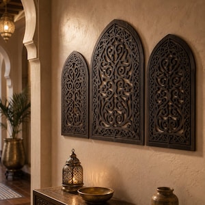 May include: Three dark brown wooden wall panels featuring intricate, symmetrical, laser-cut scrollwork patterns. Each panel has a pointed arch top, resembling a window frame, mounted side-by-side on a textured, light-colored wall surface.