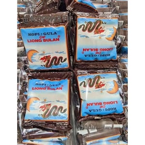 Könnte beinhalten: Mehrere Packungen Kaffee und Zucker, jede mit einem blauen Etikett mit der Aufschrift "KOPI+GULA Cap LIONG BULAN". Das Design umfasst einen Drachen, einen Mond und einen Wolkenhintergrund. Die Packungen sind in Klarsichtfolie versiegelt.