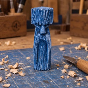 May include: A hand-carved wooden figurine of a bearded figure with a prominent hat, finished in a vibrant blue paint. The sculpture features deep, textured chisel marks throughout the surface, depicting a long beard and facial features.