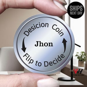 May include: A silver decision coin with the text "Decision Coin" and "Flip to Decide" around the edge. The name "Jhon" is in the center. The coin is held between two fingers.