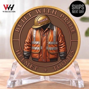 May include: A round, bronze-colored coin with a gold rim. The coin features an illustration of a construction worker's uniform and hard hat with the name "Parker" on it. The coin is inscribed with the words "Built with Pride" and "Helmet + Tools".