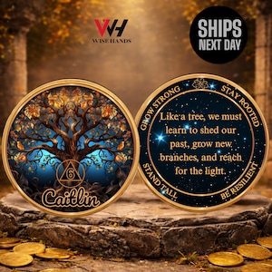 May include: Two gold-colored coins. One coin features a tree design with the name "Caitlin" and the number "6". The other coin has the text "Like a tree, we must learn to shed our past, grow new branches, and reach for the light."